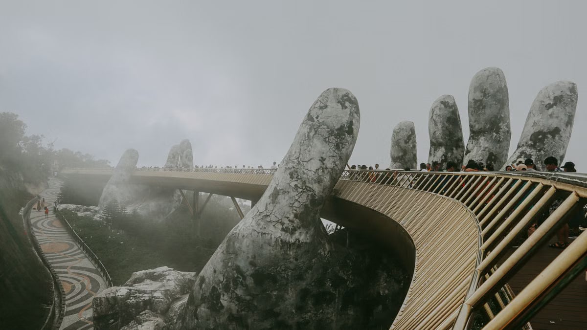 Stunning view of Golden Bridge held by stone hands enveloped in mist, Ba Na Hills.